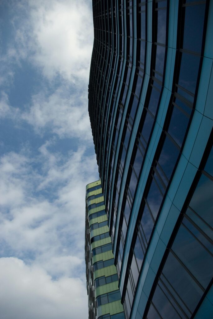 Low-angle view of modern skyscrapers with reflective windows and cloudy sky backdrop.